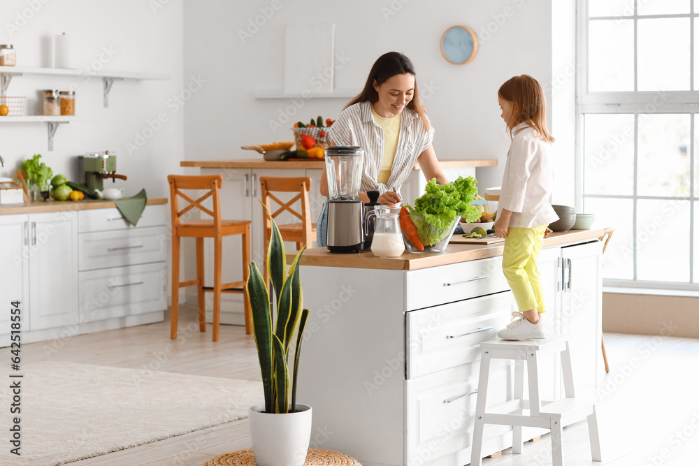 Little girl with her mother cooking healthy salad in kitchen