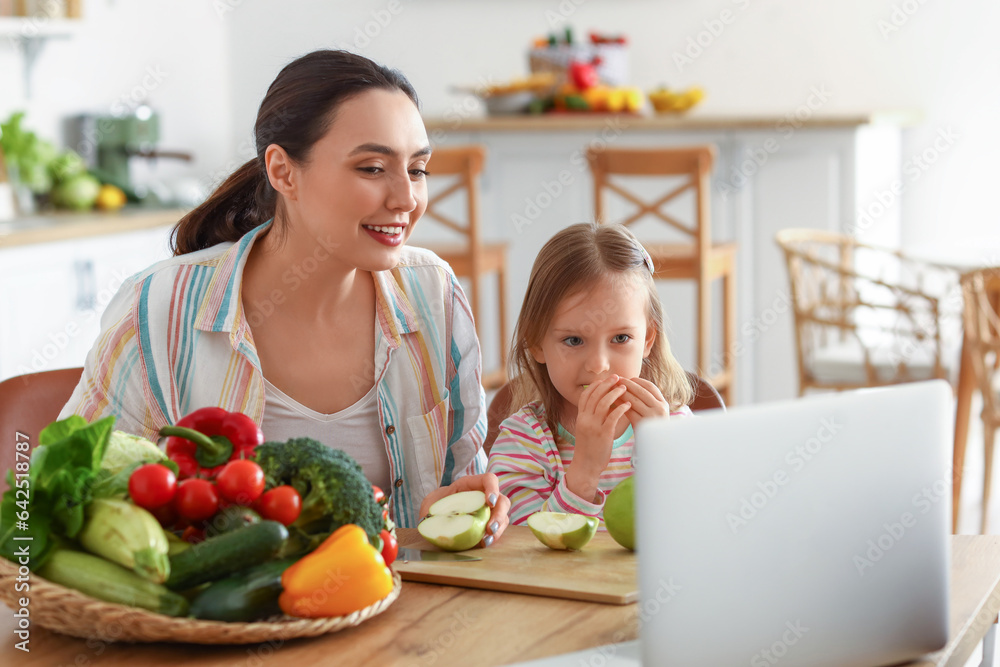 Little girl with her mother eating apples in kitchen