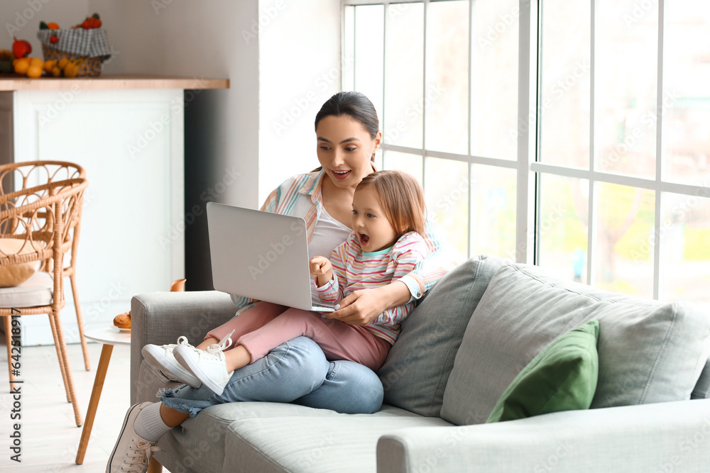 Little girl with her mother watching cartoons at home