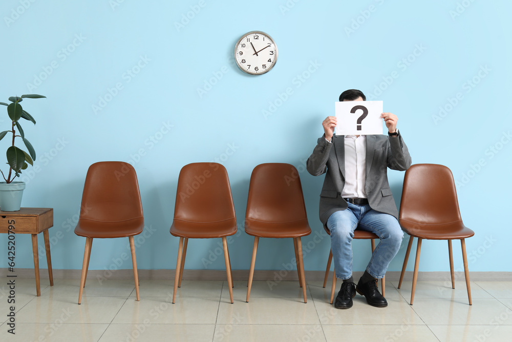 Male applicant holding paper with question mark in room