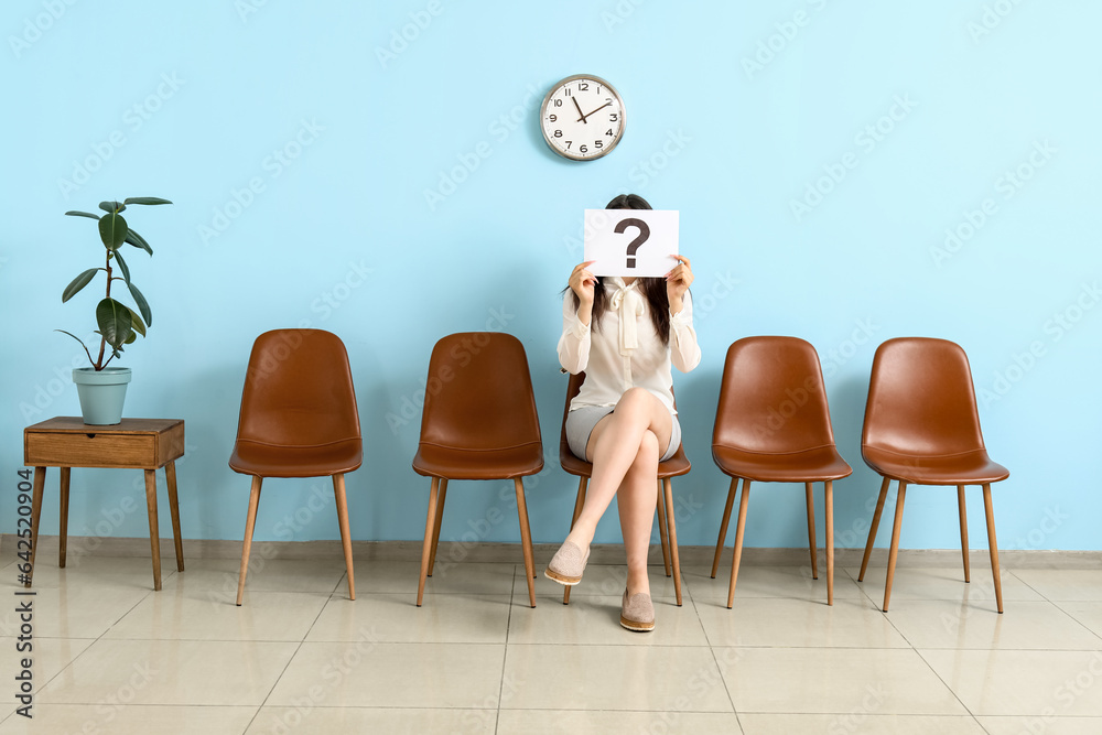 Female applicant holding paper with question mark in room