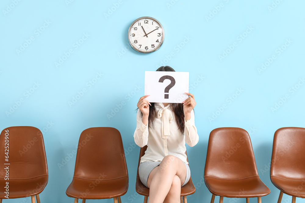 Female applicant holding paper with question mark in room