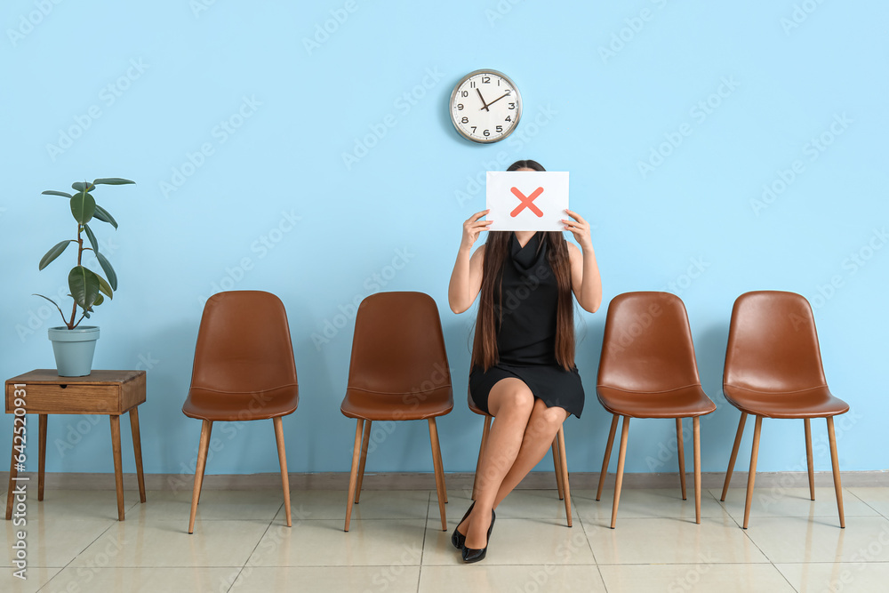 Female applicant holding paper with cross in room