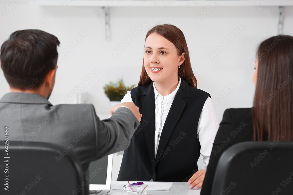 Human resources manager shaking hands with female applicant in office