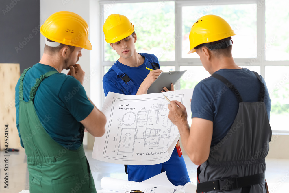 Team of male builders working with house plan in room