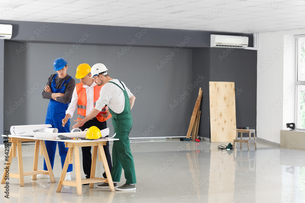 Team of male builders working in room