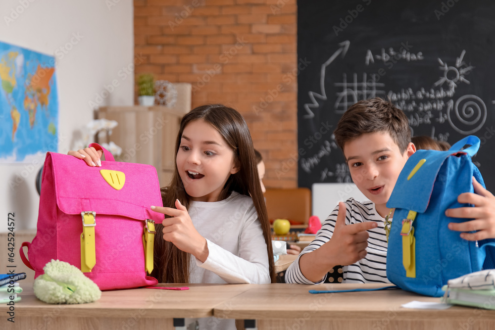 Little pupils with backpacks sitting in classroom