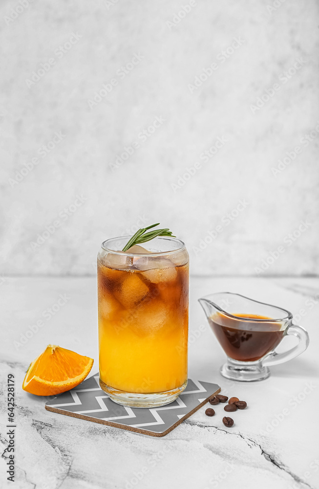 Glass of tasty orange espresso and ingredients on table