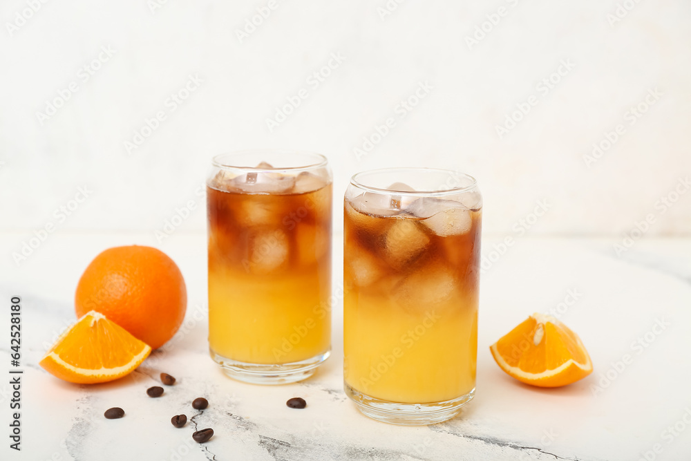 Glasses of tasty orange espresso on white table