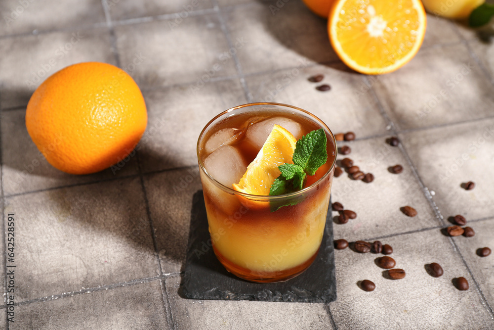 Glass of tasty orange espresso on grey tile background