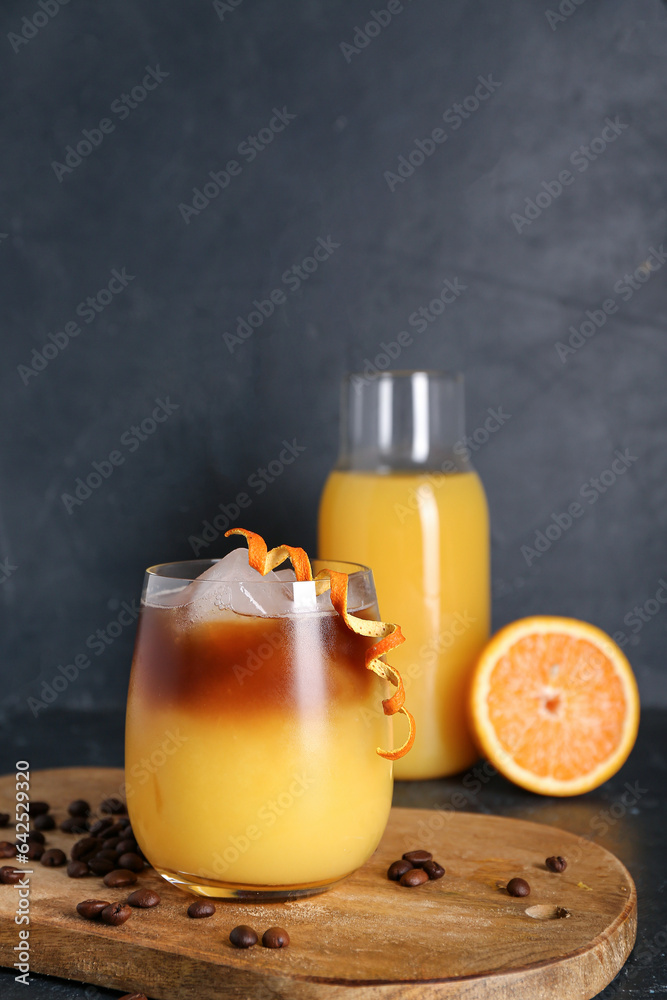 Glass of cold orange espresso on black background