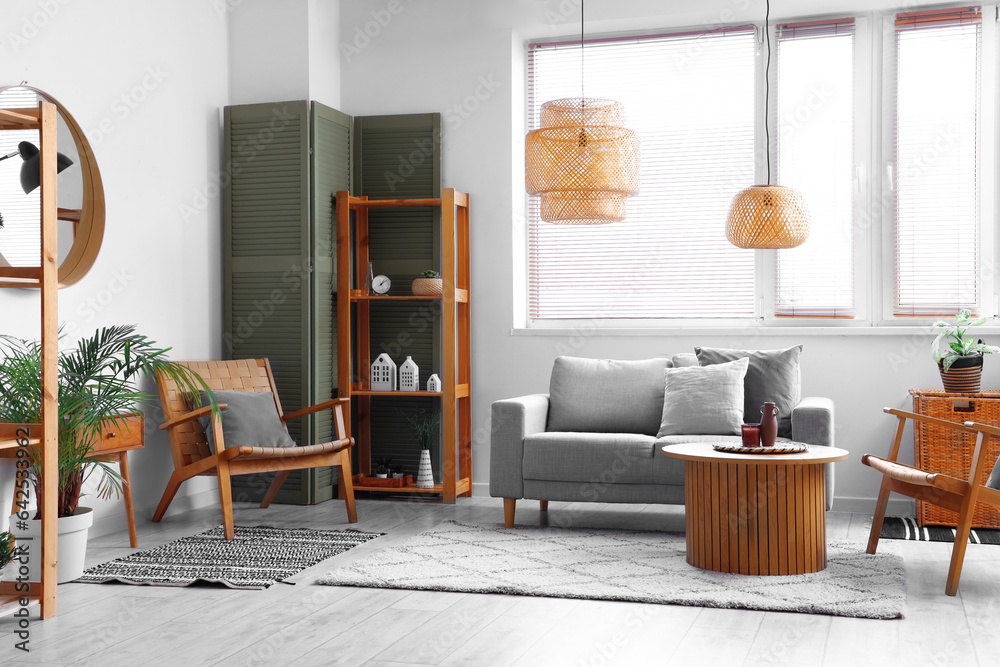 Interior of modern living room with comfortable sofa, table and folding screen