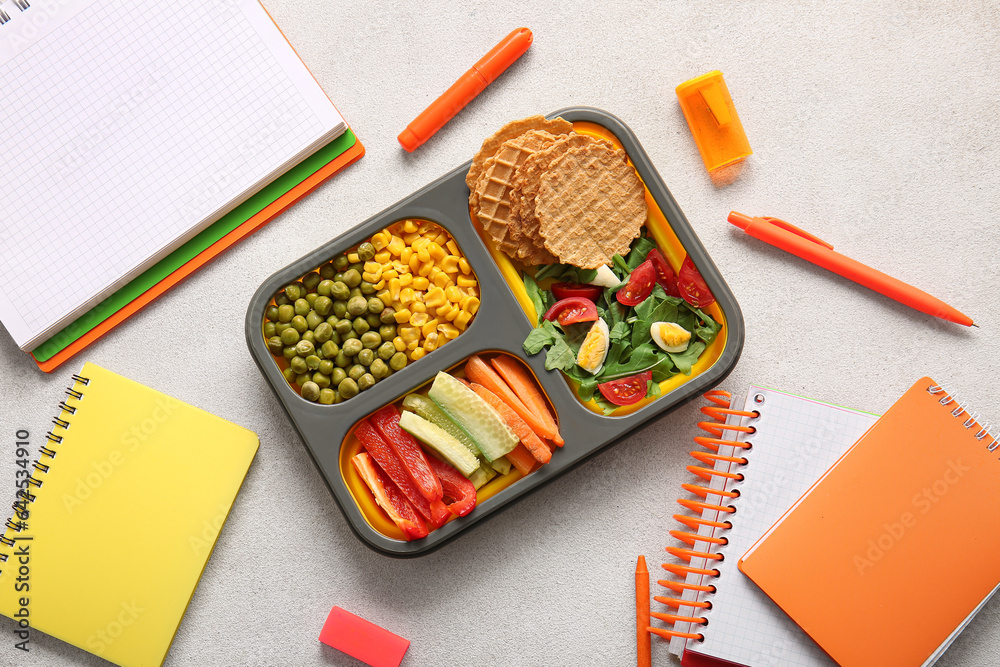 Lunchbox with delicious food and different stationery on light background