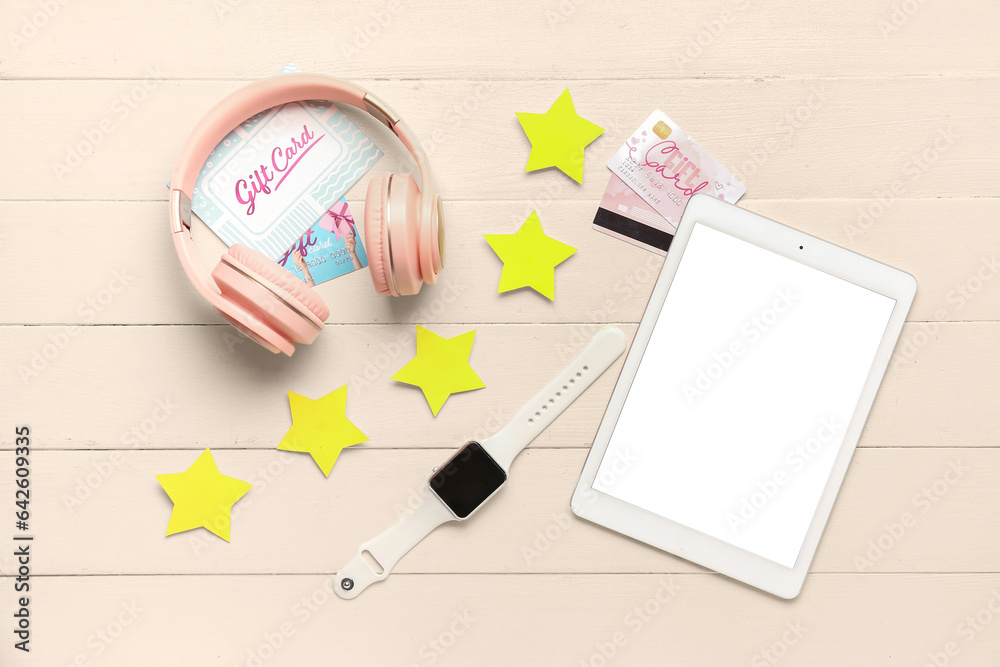 Five stars with headphones, gift cards, smartwatch and tablet computer on white wooden background. C