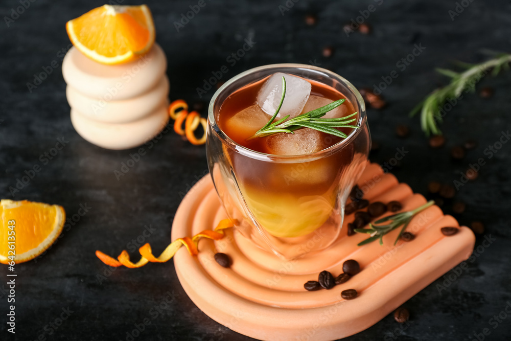 Glass of cold orange espresso on black background