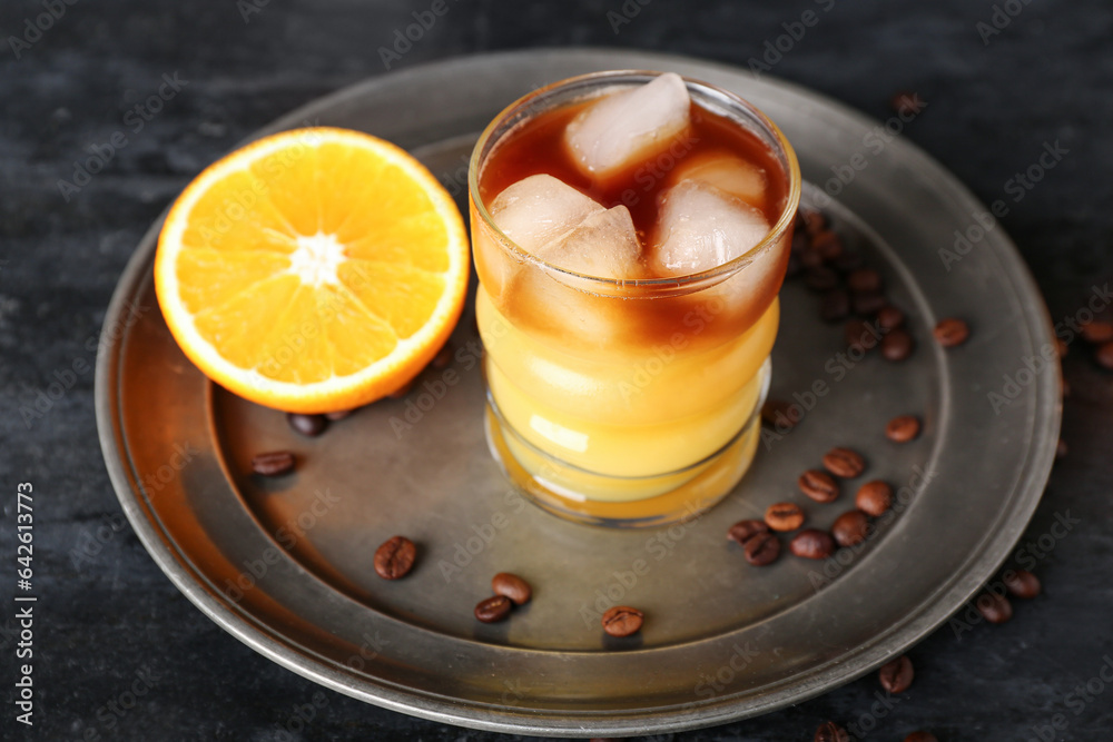 Glass of cold orange espresso on black background