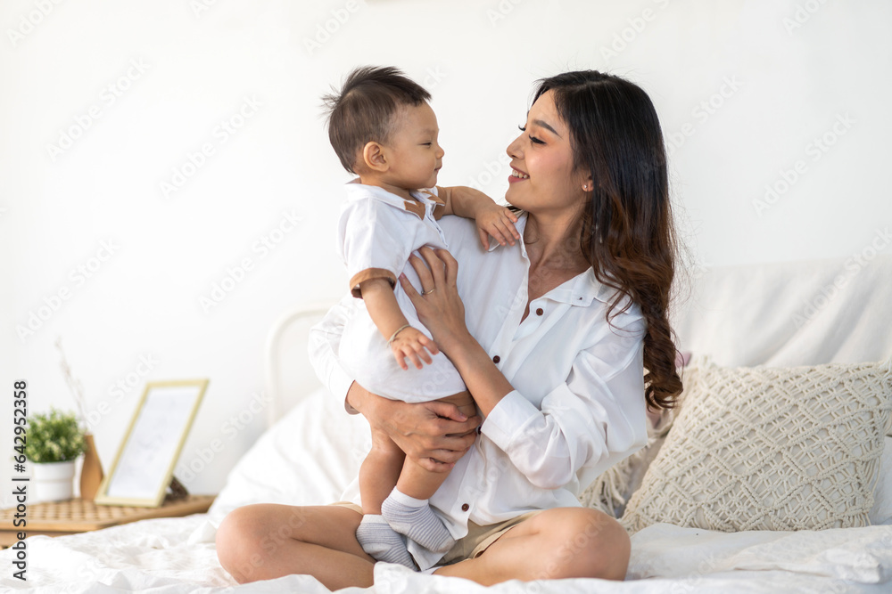 Portrait of enjoy happy love family asian mother playing with adorable little asian baby.Mom touchin