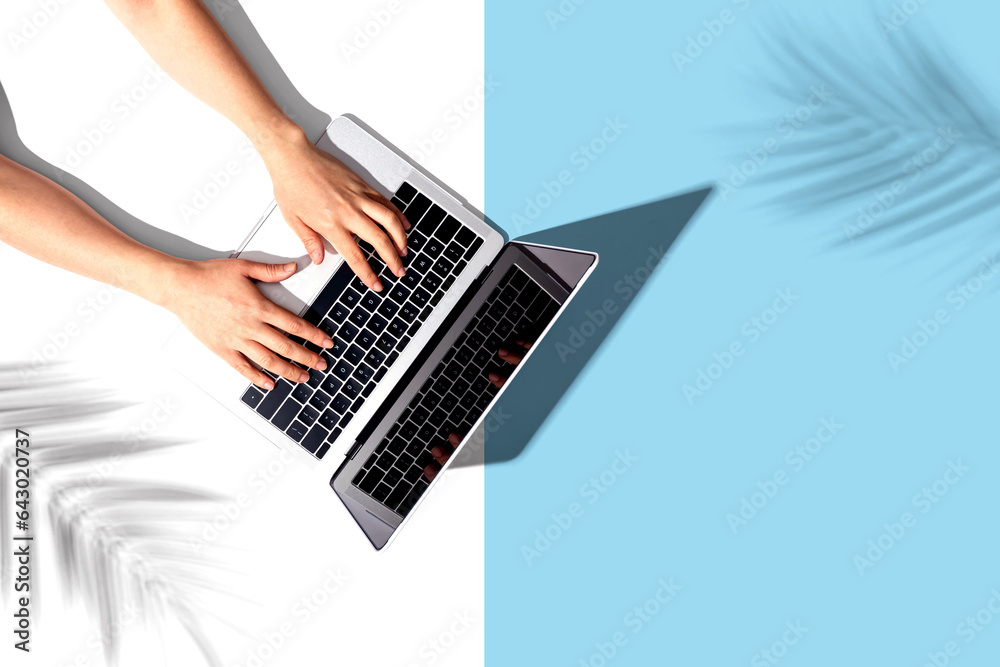 Person using a laptop computer with tropical plant shadow from above