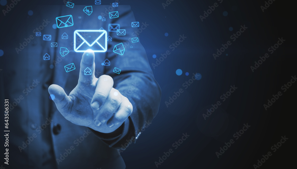 Close up of business man hand pointing at glowing email letter icons on dark blue background with mo