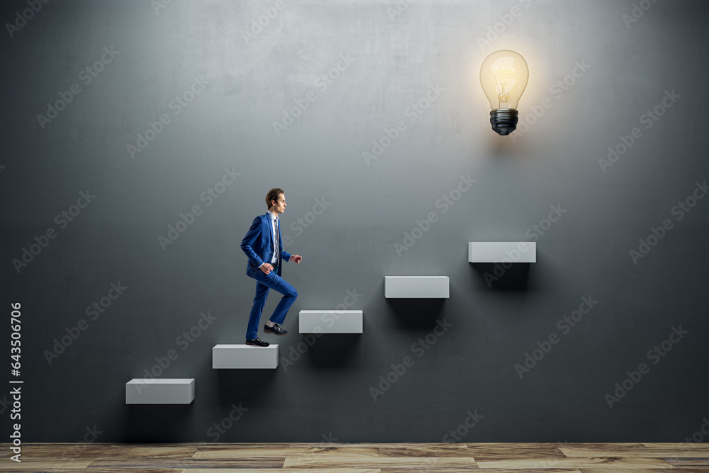 Side view of young man climbing illuminated light bulb stairs to success on concrete wall background