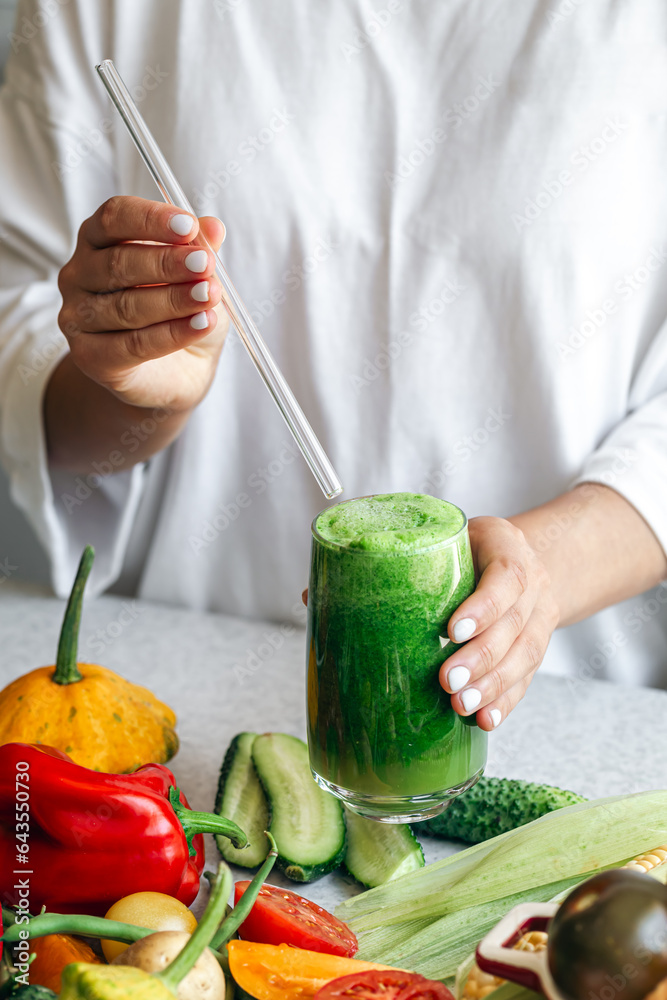 A glass of green smoothie in female hands, detox, diet and healthy eating.