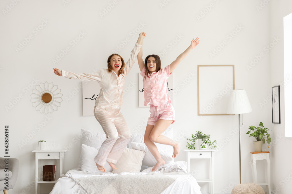 Female friends jumping on bed at home