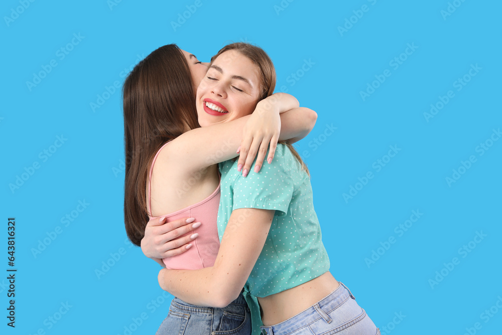 Female friends hugging on blue background