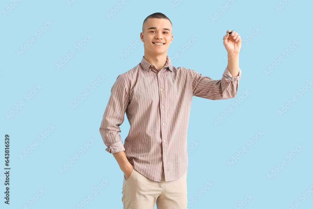 Male student with pen on blue background