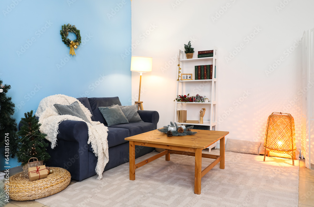 Interior of living room with sofa, coffee table, shelving unit and Christmas decorations