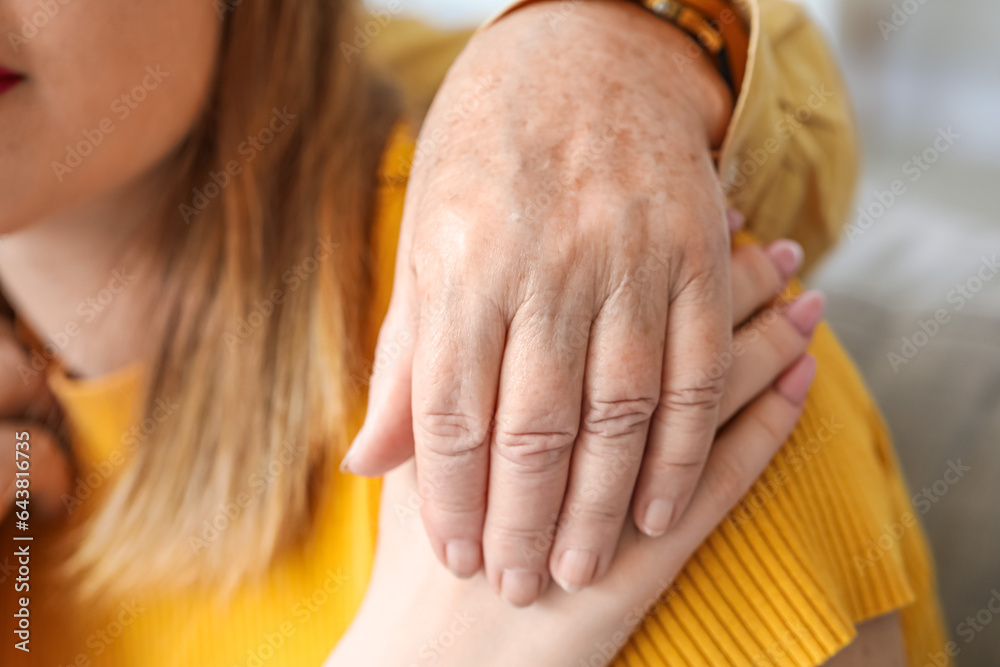 Young woman with her grandmother hugging at home, closeup