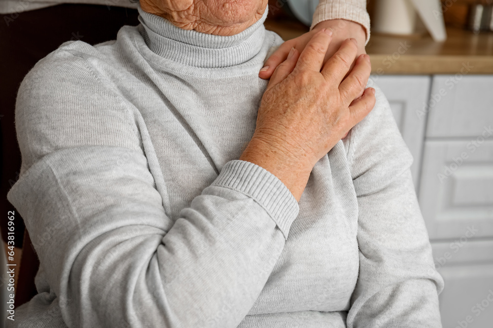 Young woman with her grandmother holding hands in kitchen, closeup