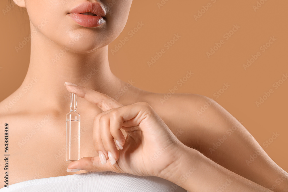 Beautiful young woman with ampule on beige background, closeup