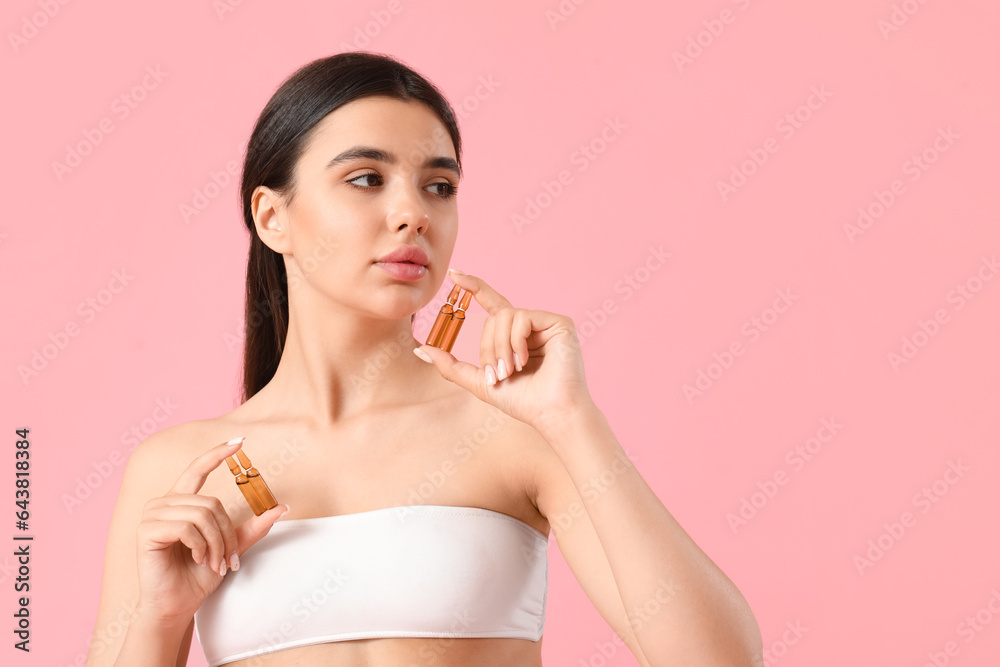 Beautiful young woman with ampules on pink background