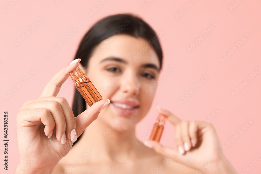 Beautiful young woman with ampules on pink background, closeup