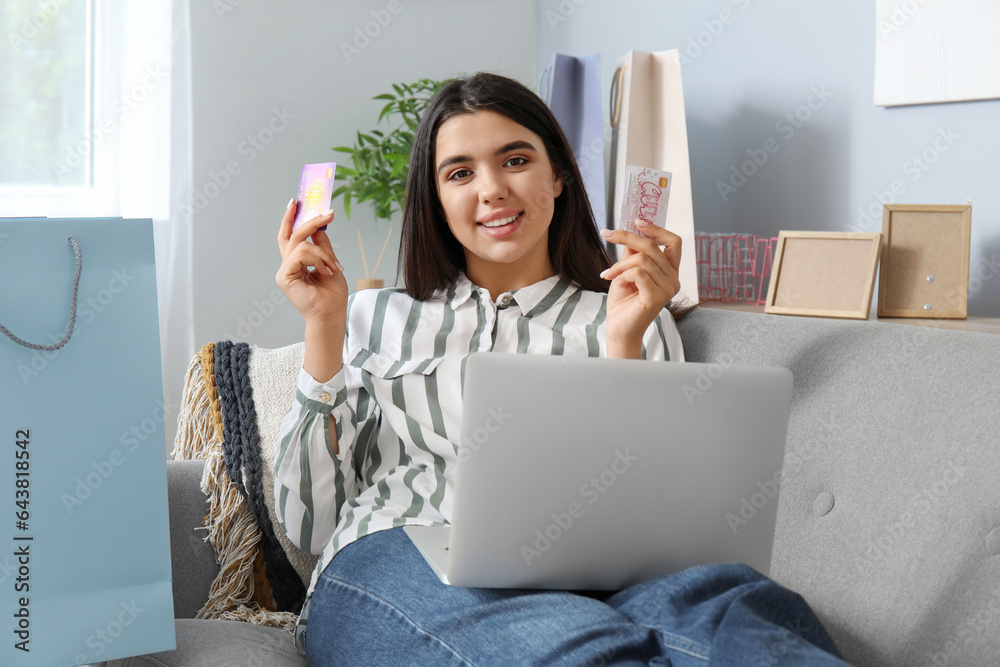 Young woman with gift cards and laptop shopping online at home