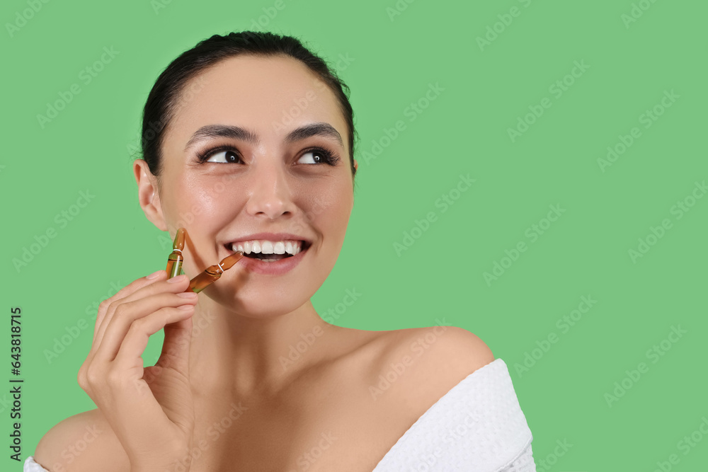 Beautiful young woman with ampules on green background, closeup