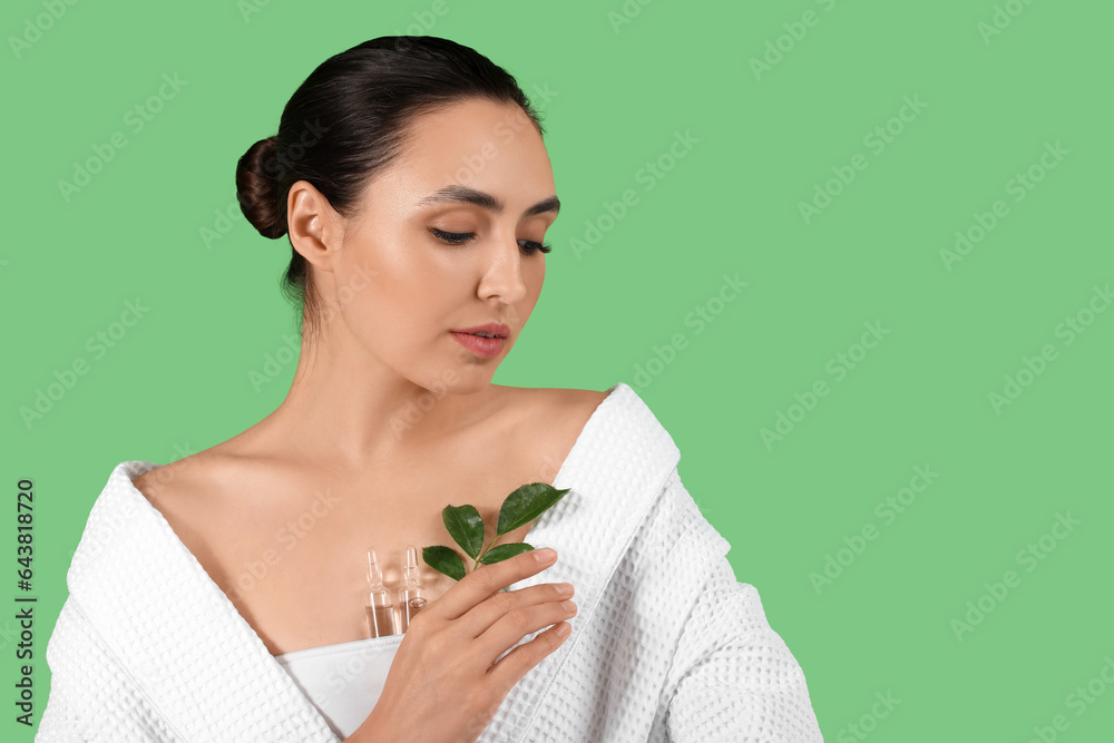 Beautiful young woman with ampules and plant branch on green background, closeup