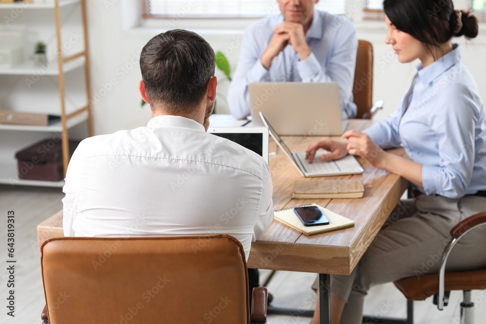 Business consultants working at table in office, back view