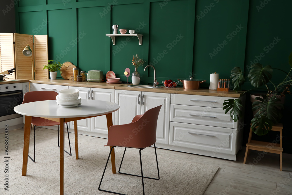 Interior of modern kitchen with white counters and dining table