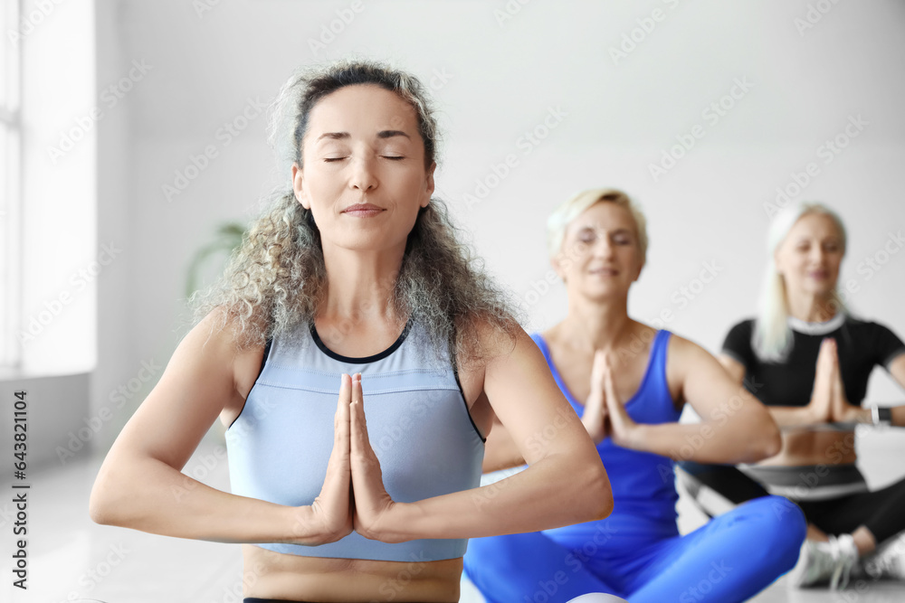 Sporty mature women meditating in gym