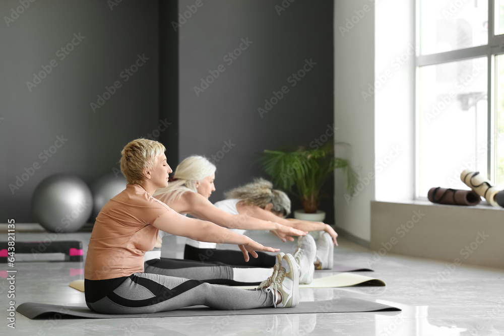 Sporty mature women practicing yoga in gym