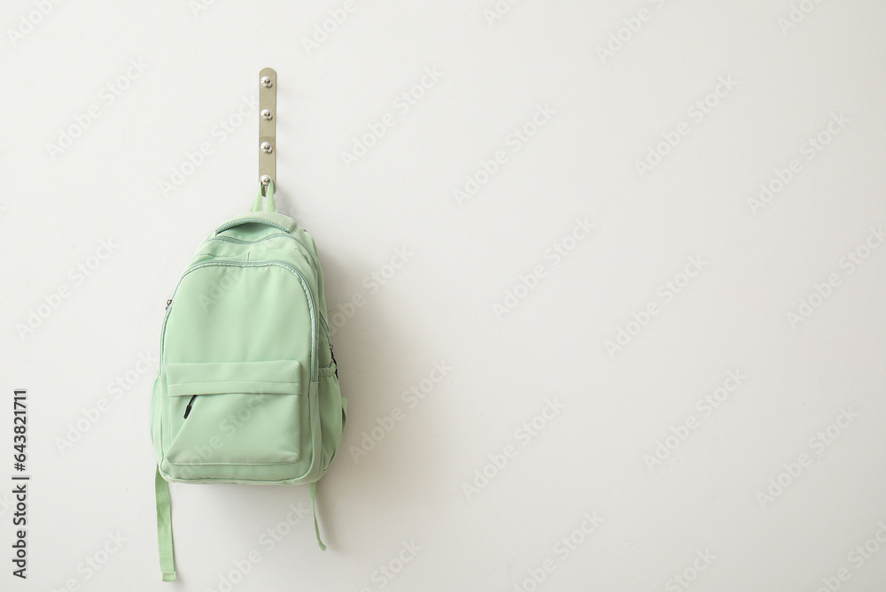 School backpack hanging on light wall