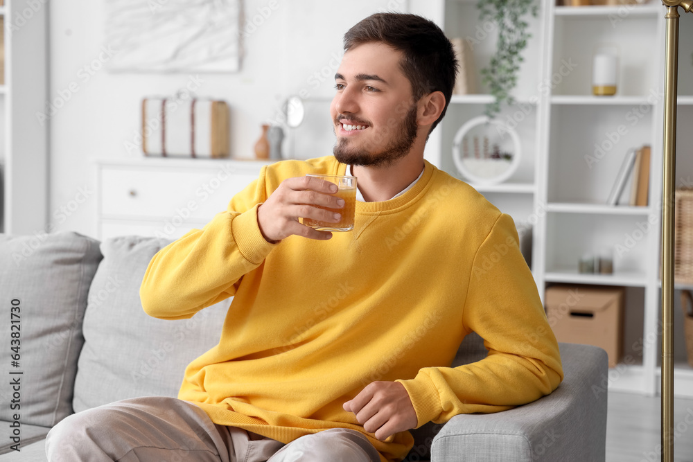 Young man with glass of juice at home