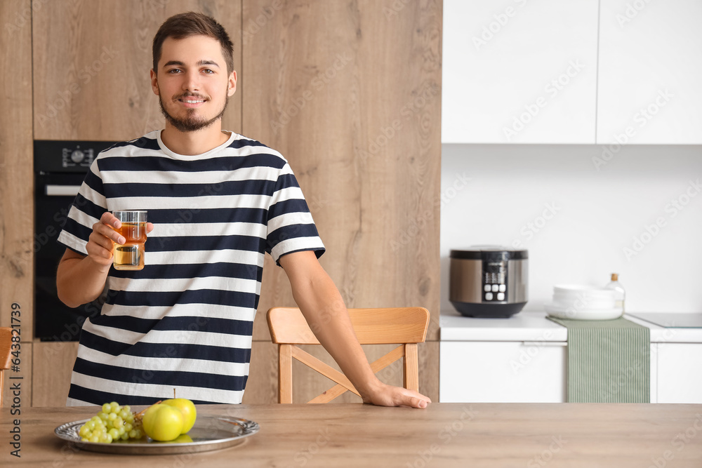 Young man with glass of juice in kitchen