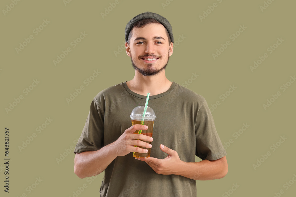 Young man with glass of juice on green background