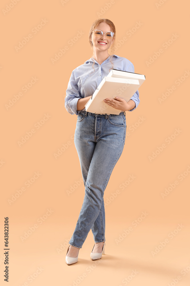 Young businesswoman with folders on beige background