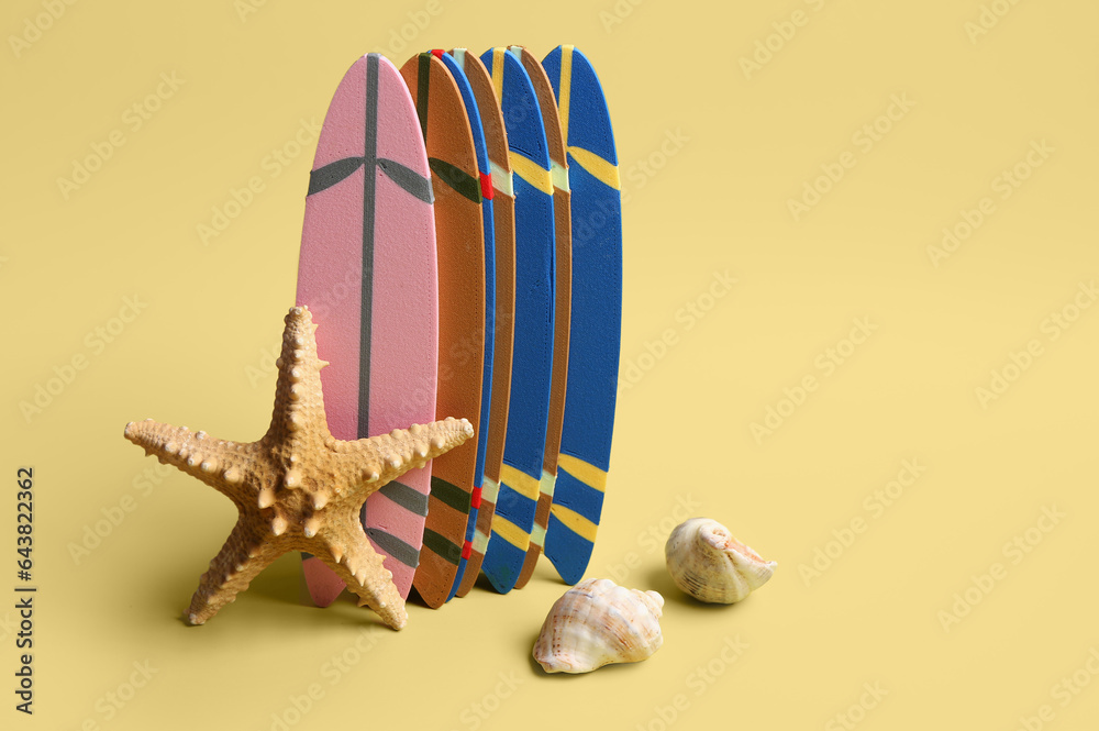 Mini surfboards, starfish and seashells on yellow background