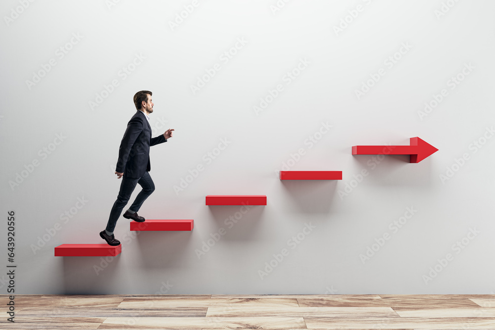 Side view of young businessman climbing red arrow stairs to success on concrete wall background in i