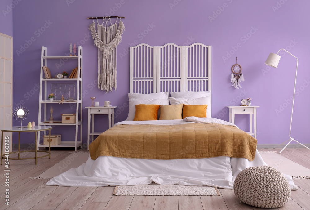 Interior of stylish bedroom with dream catcher, bed and folding screen