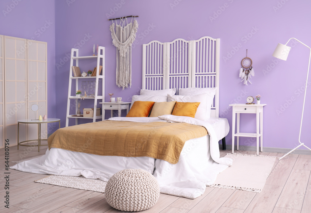 Interior of stylish bedroom with dream catcher, bed and folding screen